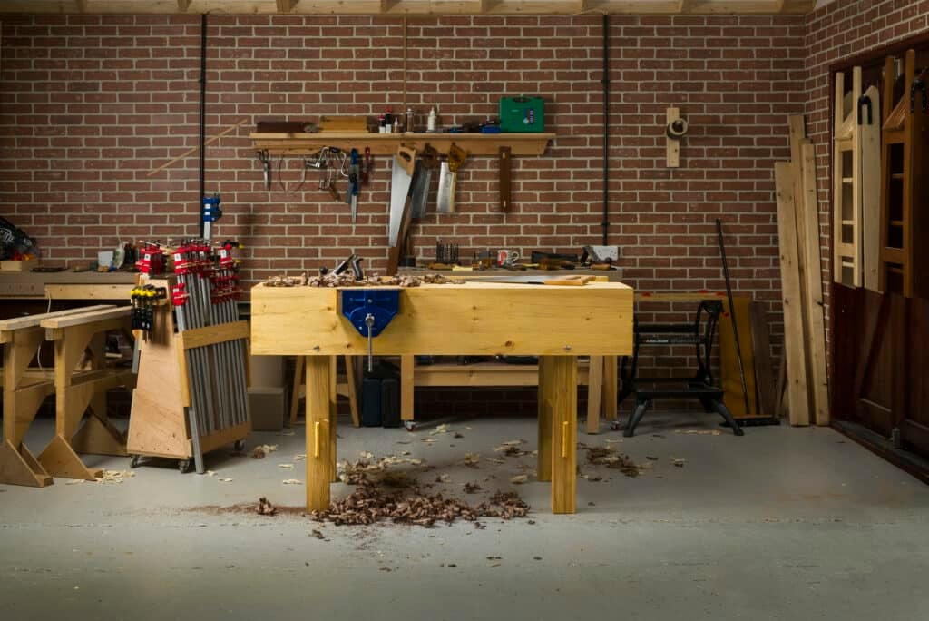 Paul Sellers' workbench in a workshop with brick walls and shavings on the floor.